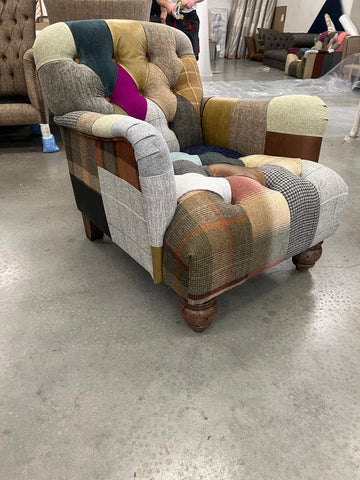 Patchwork upholstered armchair with tufted backrest and wooden carved legs on showroom floor
