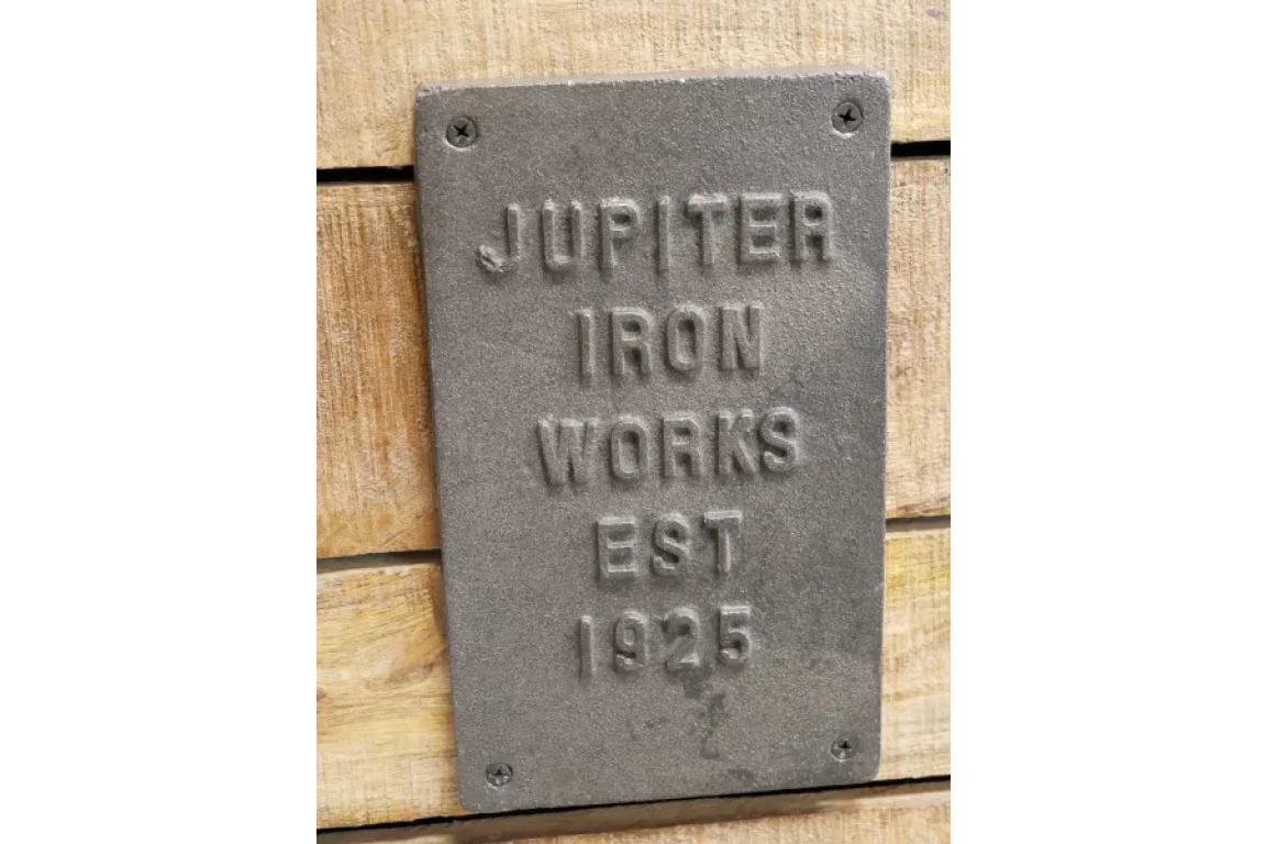 cast iron works plaque with embossed lettering on wood panel