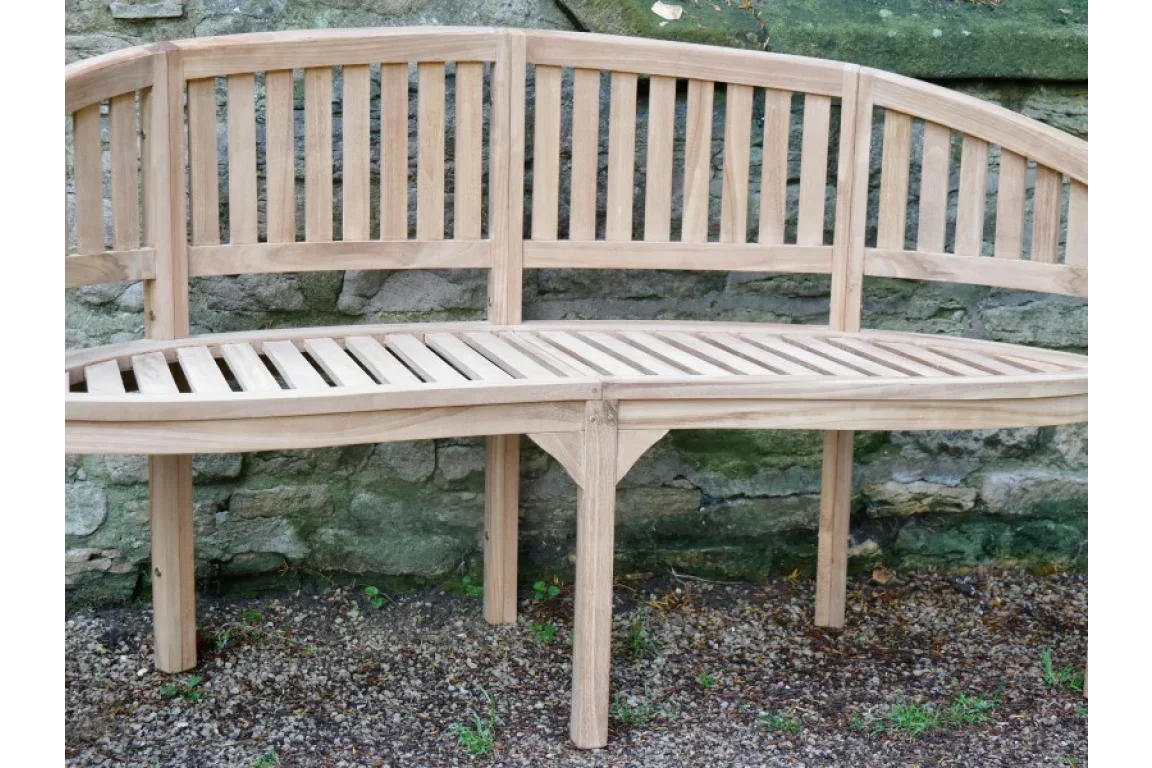 Corner wooden garden bench with slatted seat and back, placed against a stone wall