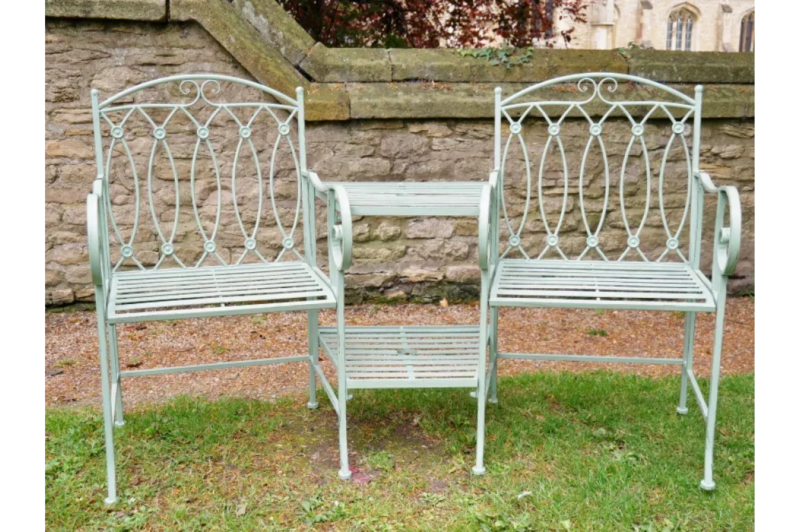 Metal garden love seat bench with centre table and decorative backrest on grass