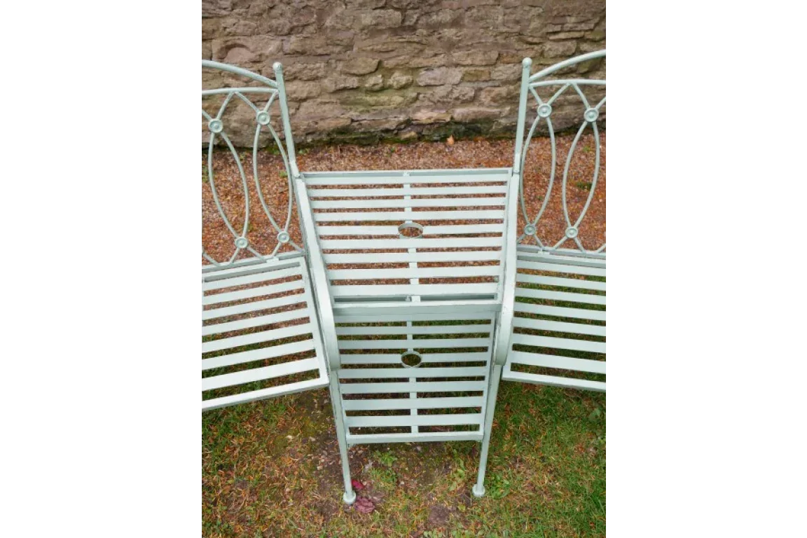 Green metal garden bench with slatted seats and table, decorative oval backrests