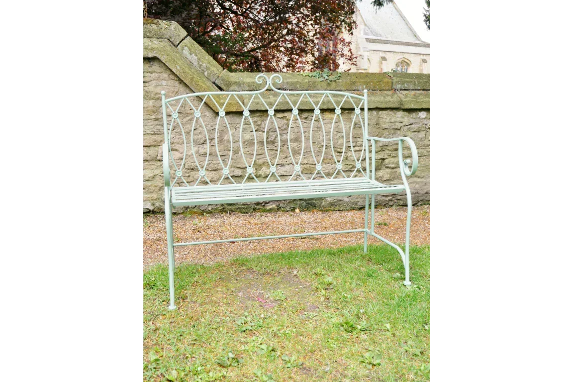 Metal garden bench with decorative backrest and curved armrest on lawn