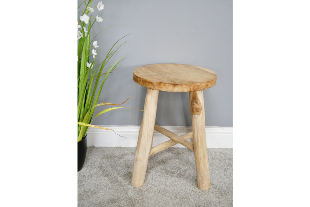 Round wooden stool with three thick legs and a cross support, shown at slight angle on gray carpet.