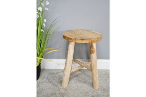 Round wooden stool with three thick legs and a cross support, shown at slight angle on gray carpet.