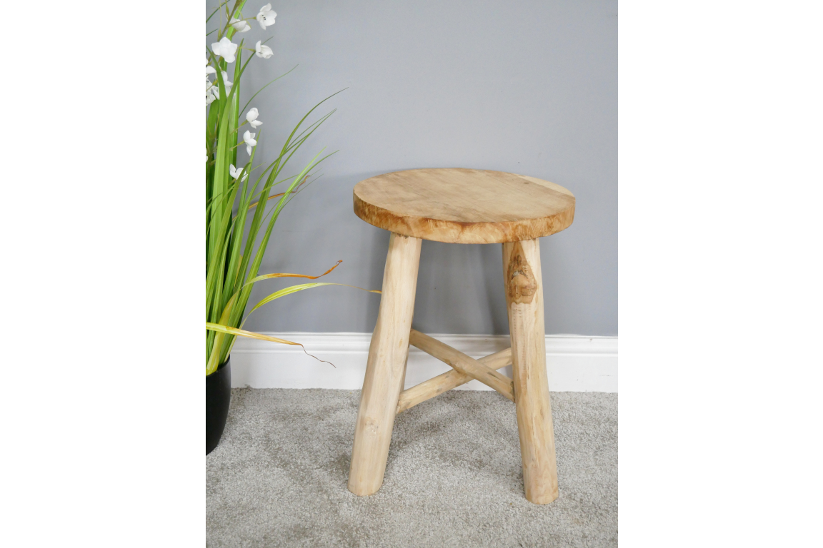 Round wooden stool with three thick legs and a cross support, shown at slight angle on gray carpet.