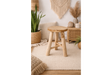 Round wooden stool with three legs in a beige, bohemian-style room setting with plants and woven decor.