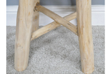 Close-up detail view of light wood stool legs with crossbars on a grey carpet floor against white wall baseboard.