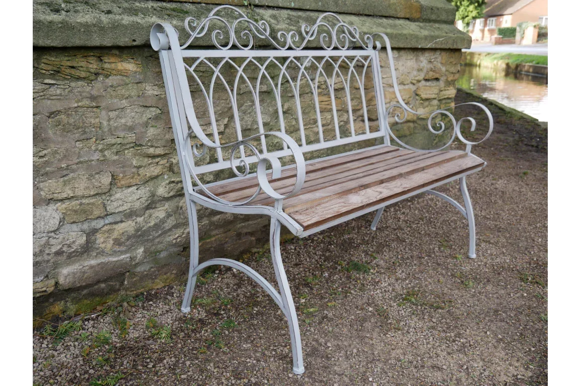 Metal garden bench with wooden slats and decorative scroll armrests outdoors