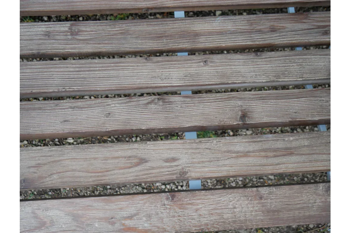Close view wooden bench slats with natural grain over gravel ground