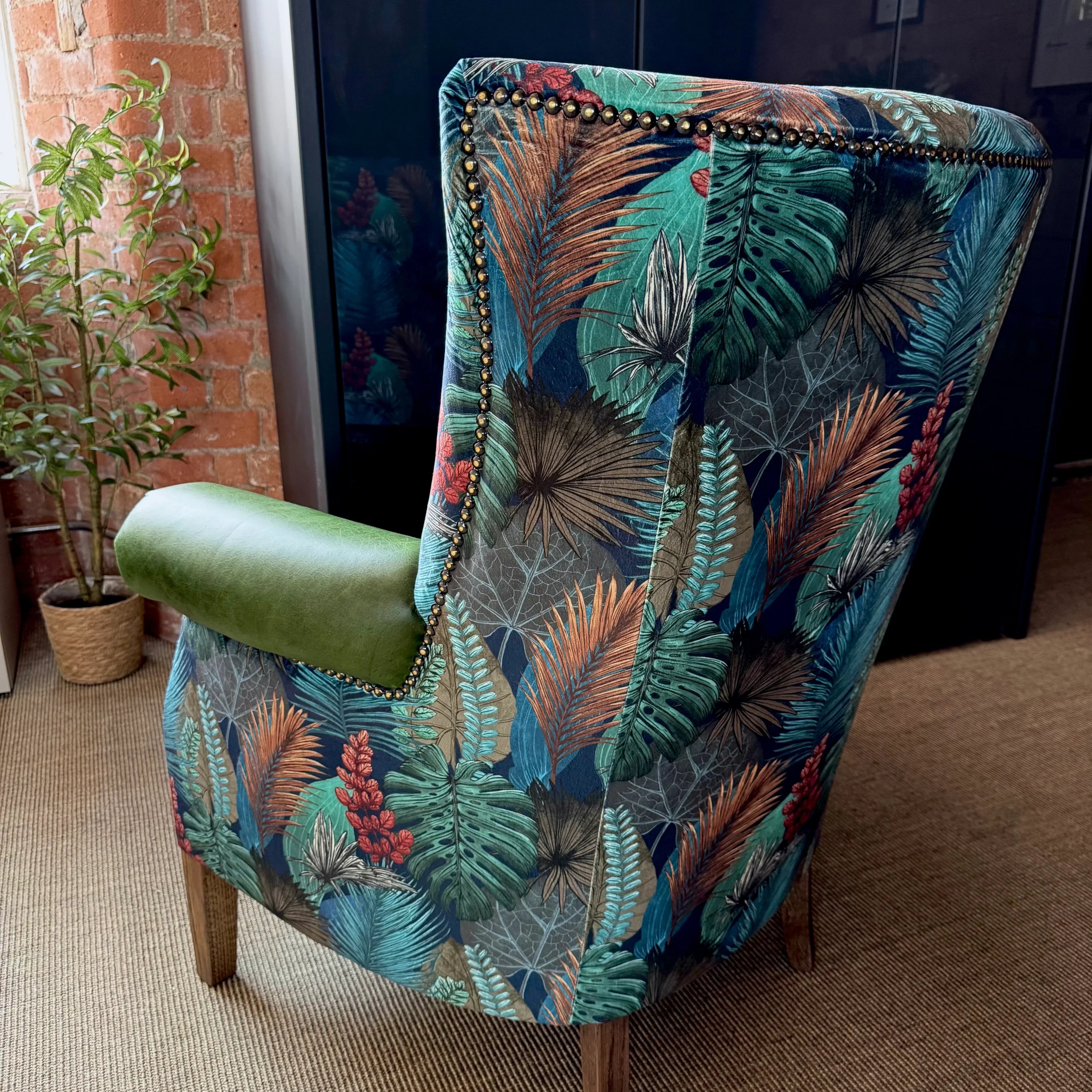 Patterned accent armchair with leaf print upholstery and wooden legs in living room setting