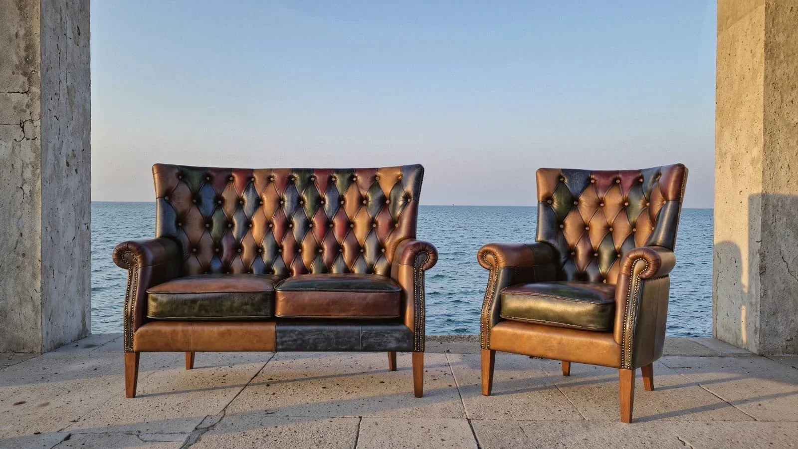 Brown leather Chesterfield sofa and armchair set with button tufting near the sea