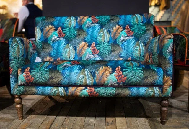 Tropical print fabric sofa with wooden legs on wooden floor