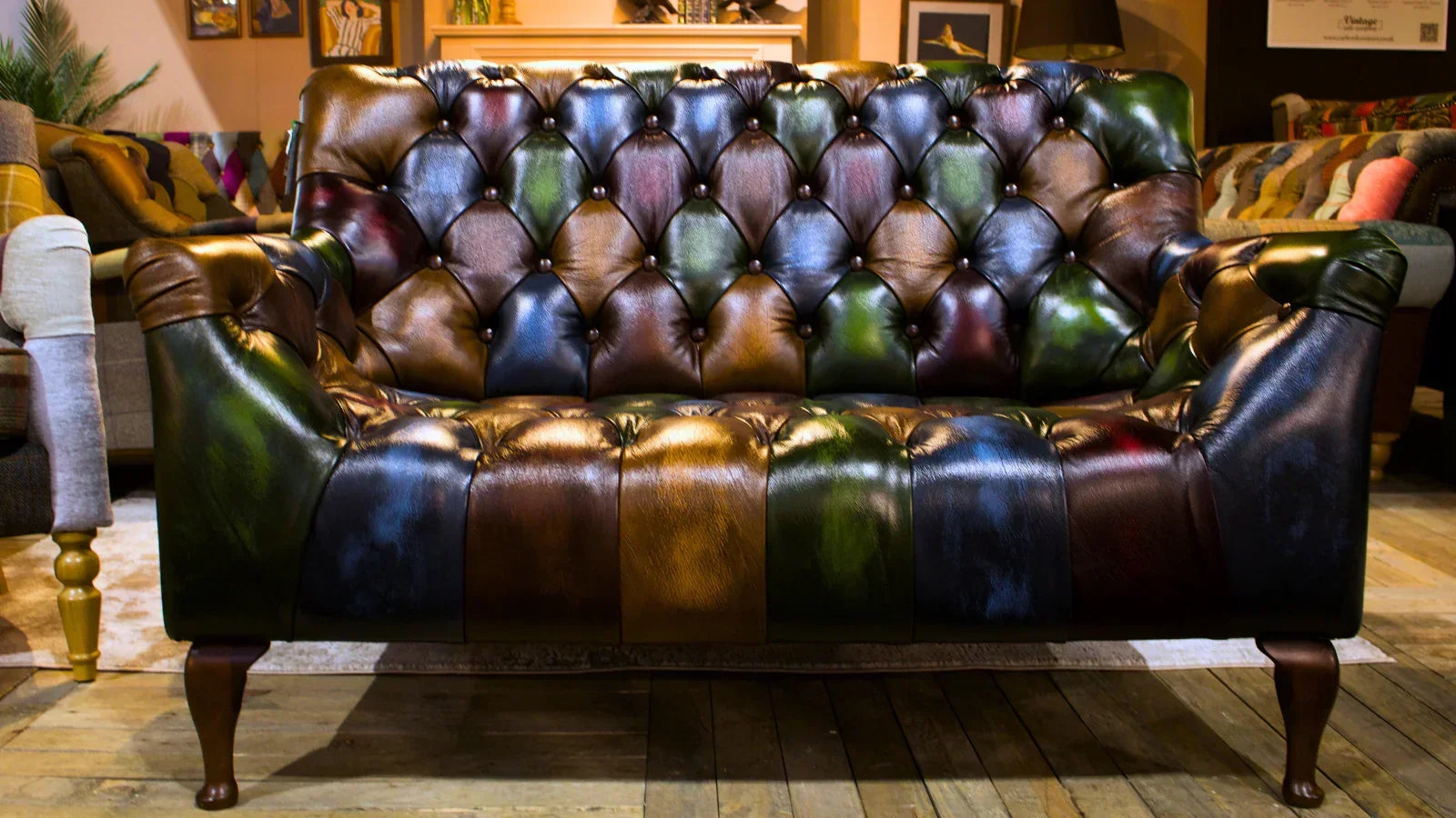 Chesterfield sofa with multicoloured leather upholstery and button-tufted backrest in lounge setting