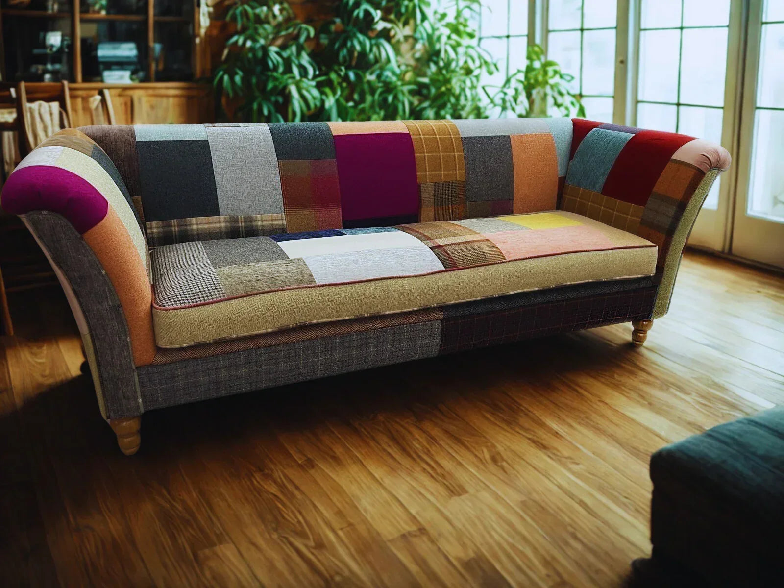 Patchwork fabric sofa with multicolored upholstery in bright living room with wood flooring