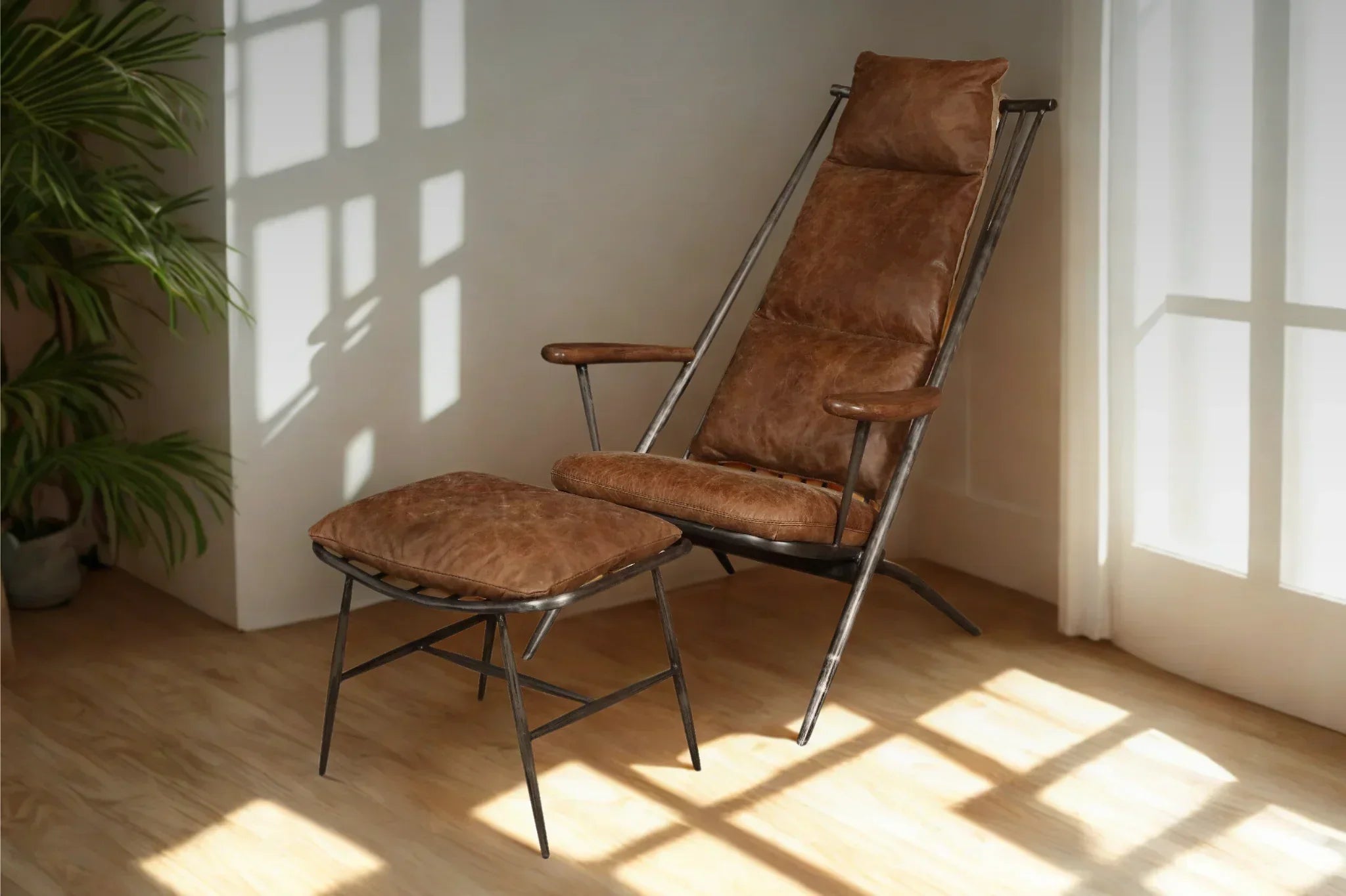 Brown leather armchair with metal frame and matching footstool in sunlit living room