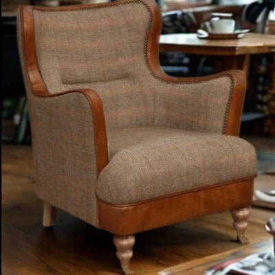 Brown fabric armchair with leather trim and wooden legs in a living room setting