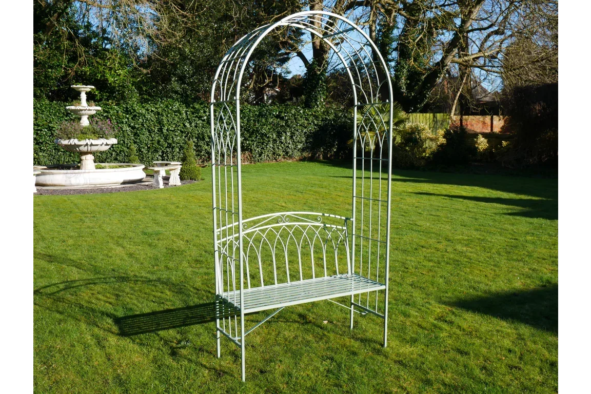 Metal garden bench with decorative arch frame on grass lawn