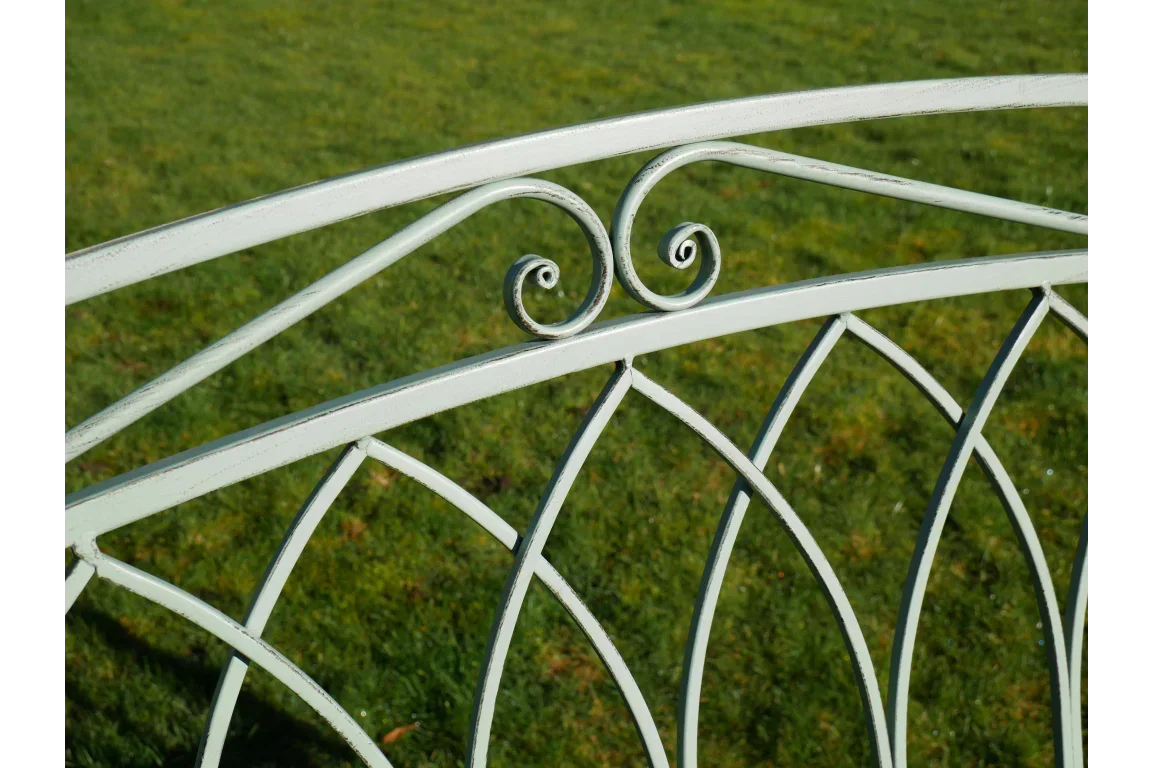 White metal garden bench backrest with decorative scrollwork design on lawn