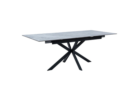 A rectangular dining table with a gray stone-look top and a black metal X-shaped pedestal base, shown on a plain white background.
