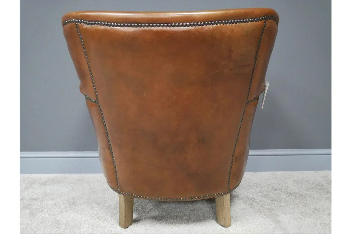 Brown leather accent chair rear view with nailhead trim and wooden legs on carpet