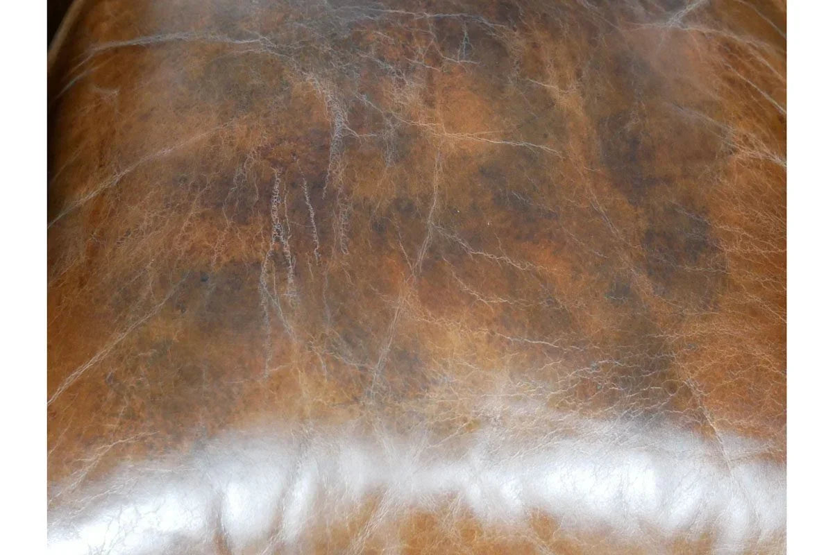 Close-up of distressed brown leather sofa cushion detail