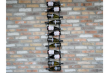 Black metal vertical wine bottle holder mounted on a multicolored brick wall, holding alternating bottles horizontally.
