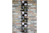 Vertical black metal wine bottle holder mounted on a multicolored brick wall with ten bottles displayed horizontally.