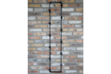 Tall black metal wine bottle holder with multiple circular holders mounted vertically on a brick wall.