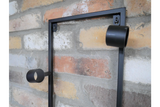 Black metal wine bottle holder mounted on a multicolored brick wall, side angle view.