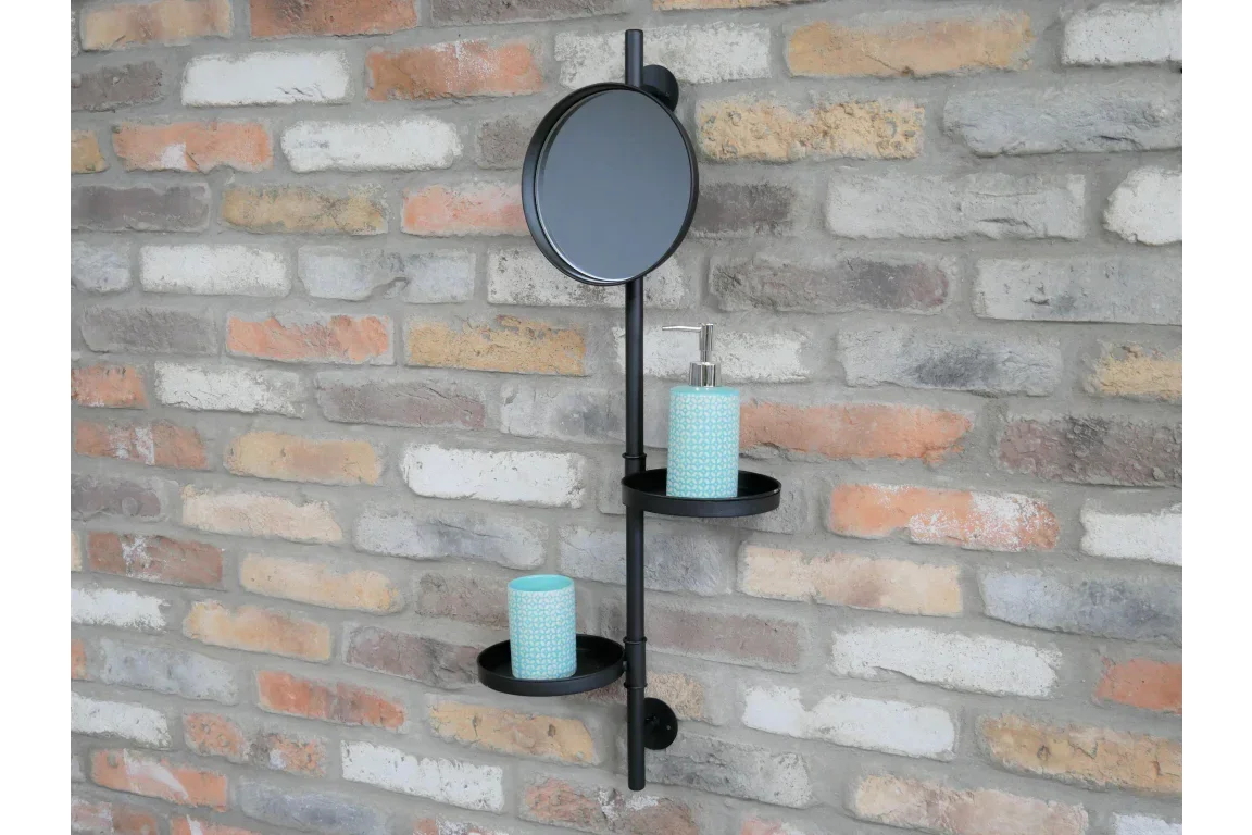 Black metal wall shelf with round mirror and two trays on exposed brick wall