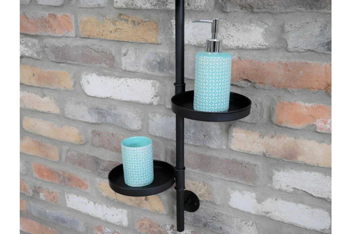 Ceramic soap dispenser and tumbler set with blue pattern on black wall shelf against brick wall