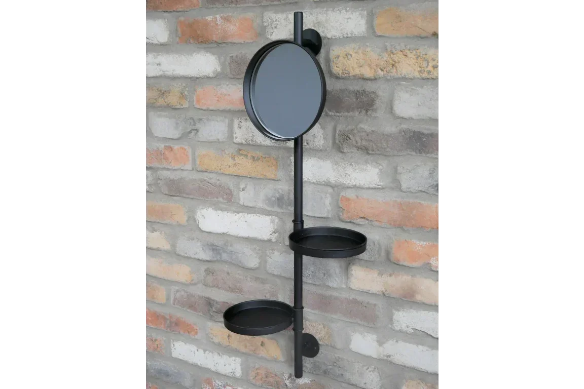Black metal wall shelf with round mirror and two circular trays on brick wall