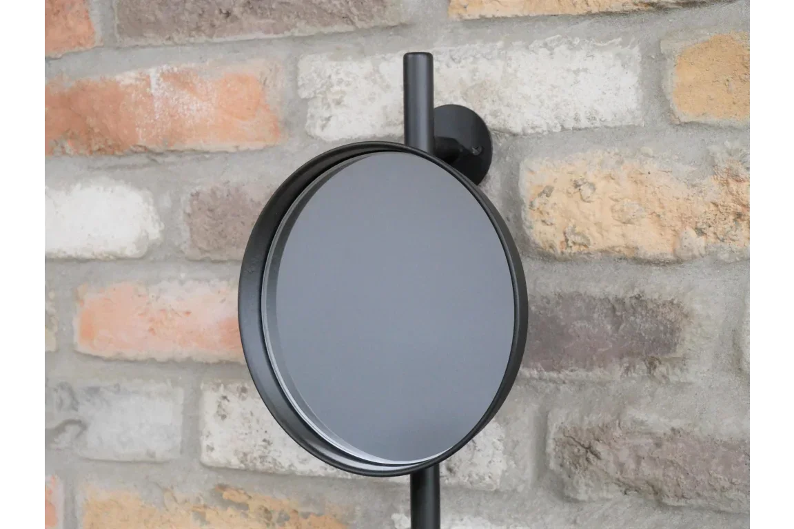 Round black wall mirror with slim frame mounted on brick wall