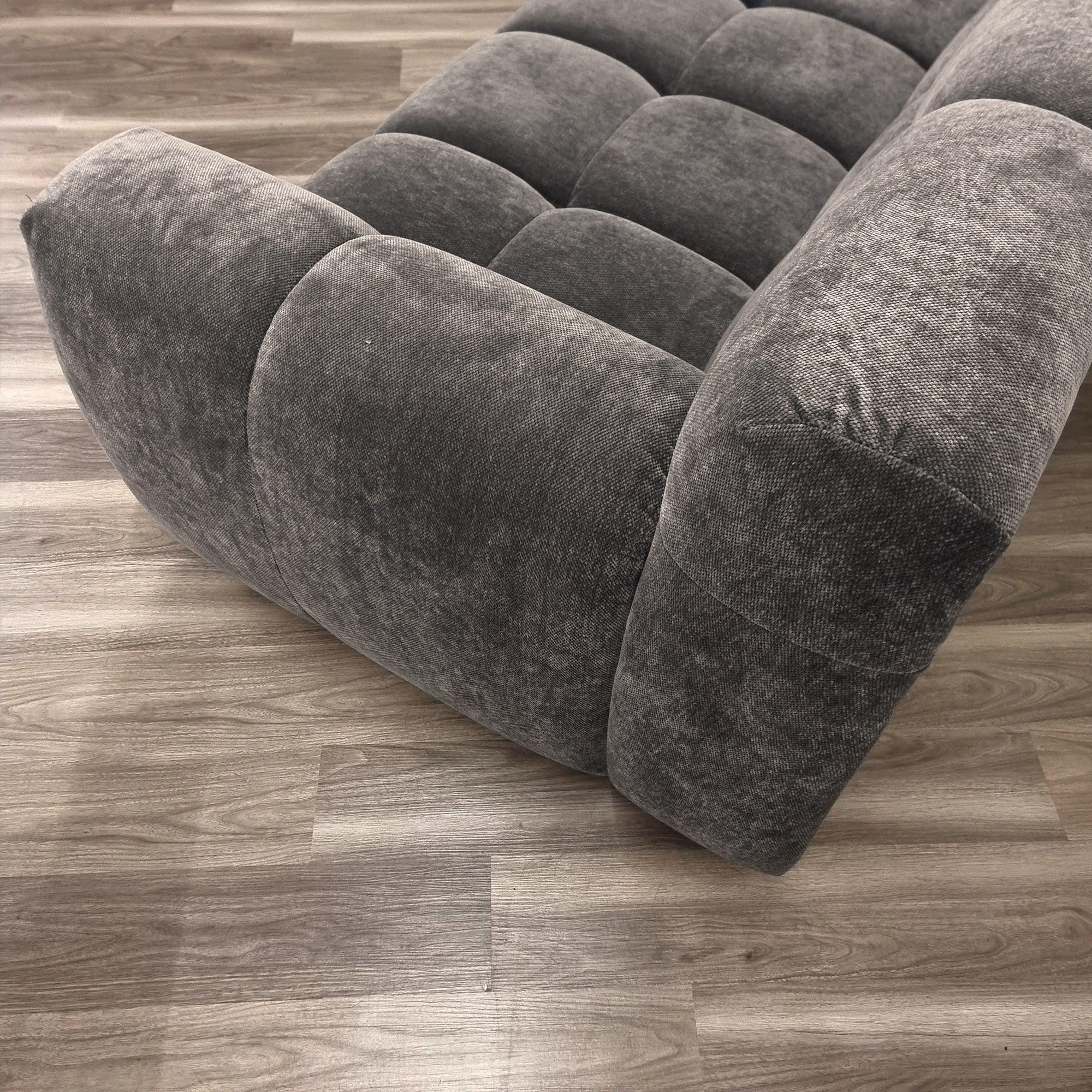 Grey fabric sofa armrest and seat detail on wood flooring