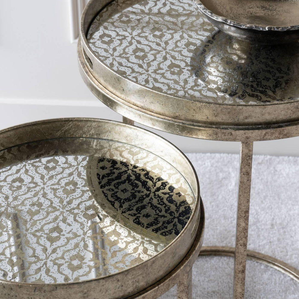 Antique gold tray tables with intricate mirrored patterns and a decorative bowl.