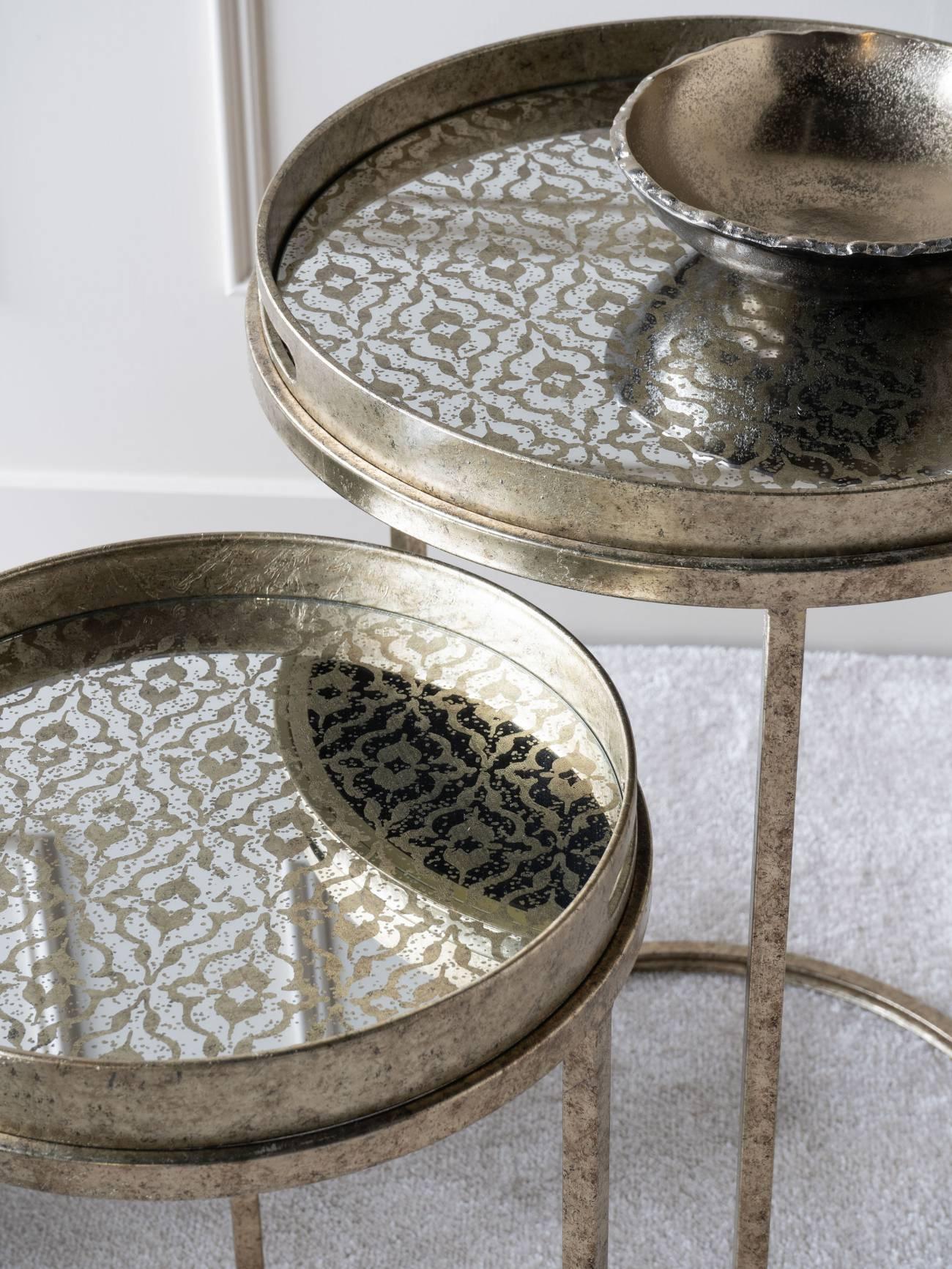 Antique gold tray tables with intricate mirrored patterns and a decorative bowl.