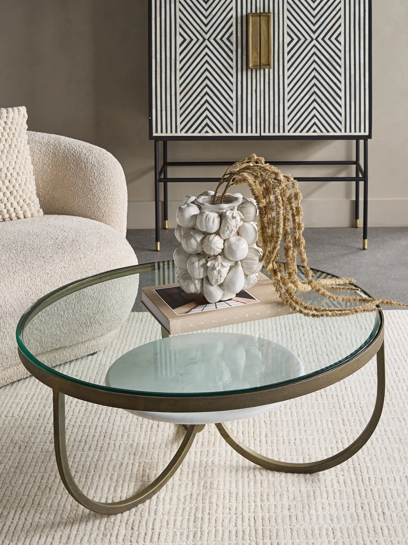 Round glass coffee table with gold iron legs in a stylish living room.