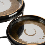 Black and gold round tables with swirling pattern and raised edges.