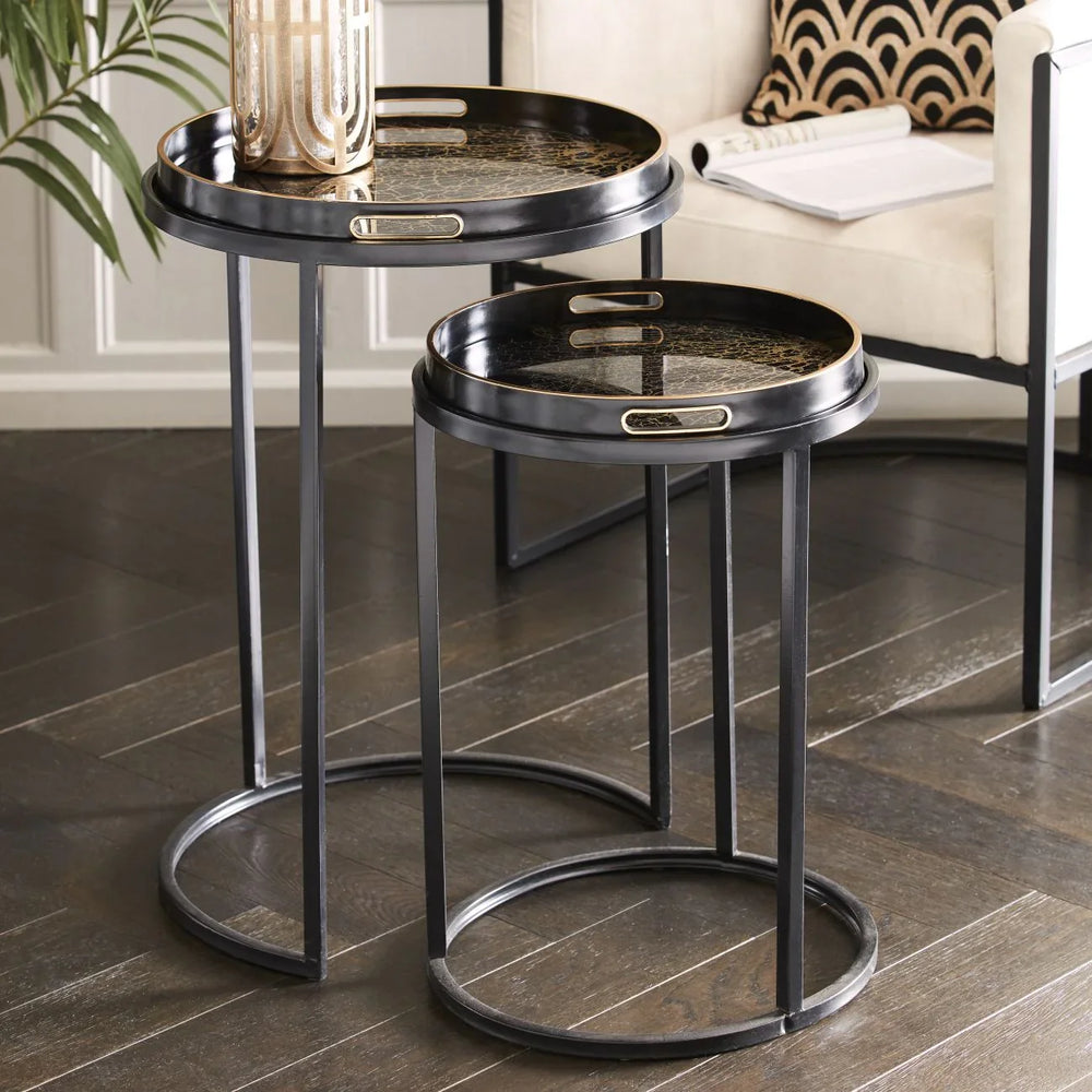 Black metal side tables with intricate tray tops in a modern living room setting.