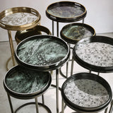 Assorted decorative tray tables with artistic patterns and sleek metal legs.