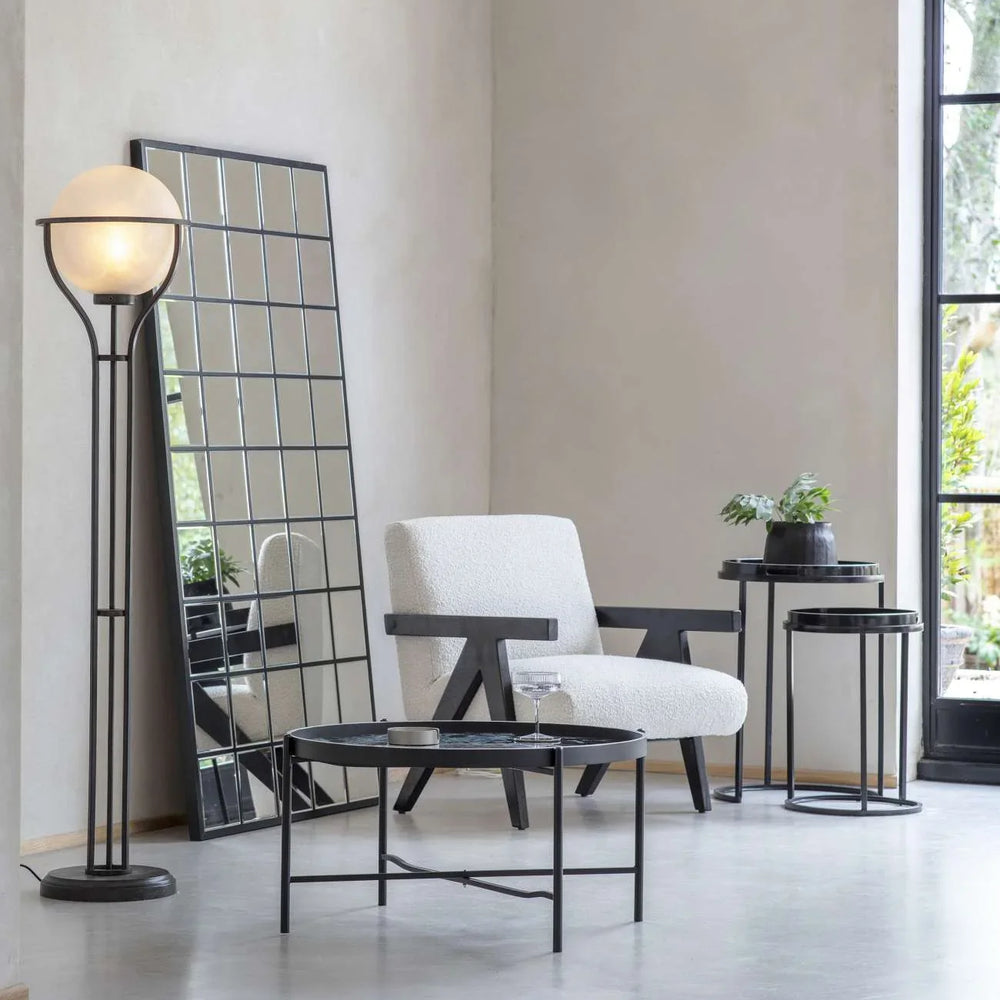 Black and white side tables in modern living room with armchair and floor lamp.