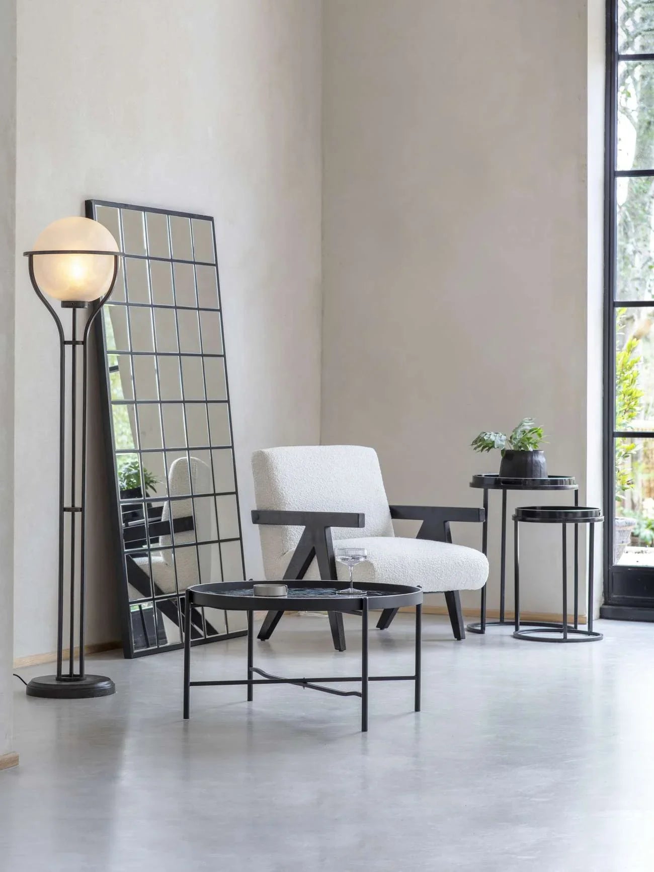 Black and white side tables in modern living room with armchair and floor lamp.