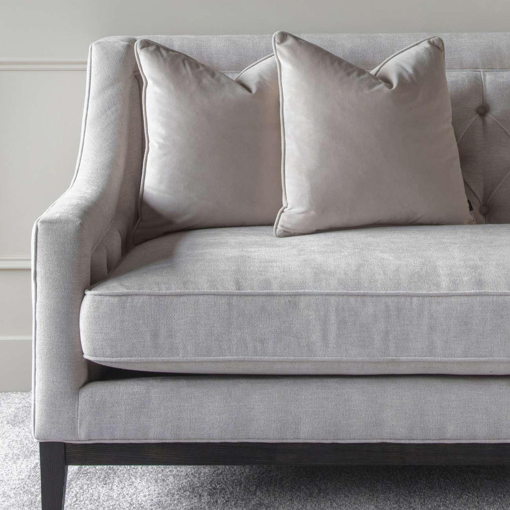 Ivory fabric sofa with buttoned back and plush cushions on grey carpet.