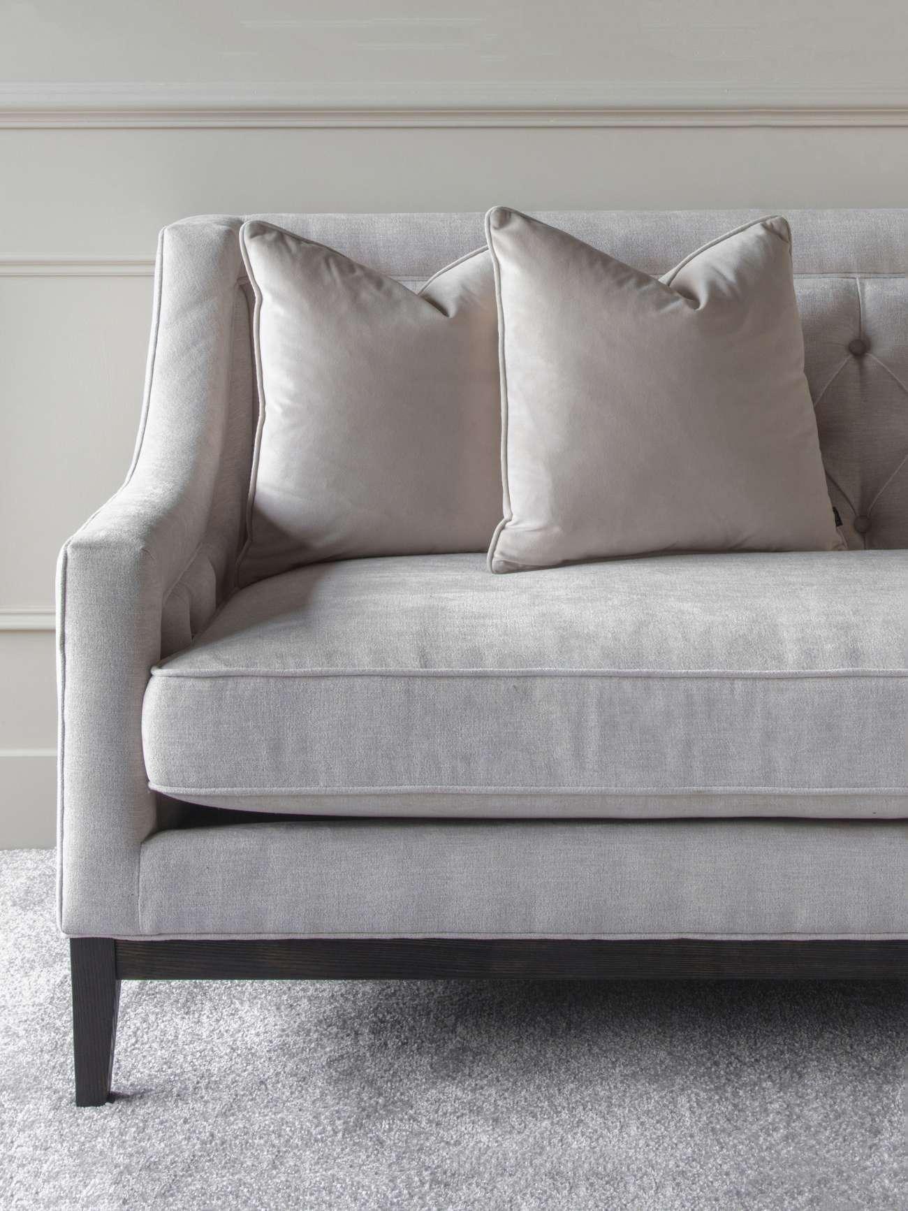 Ivory fabric sofa with buttoned back and plush cushions on grey carpet.