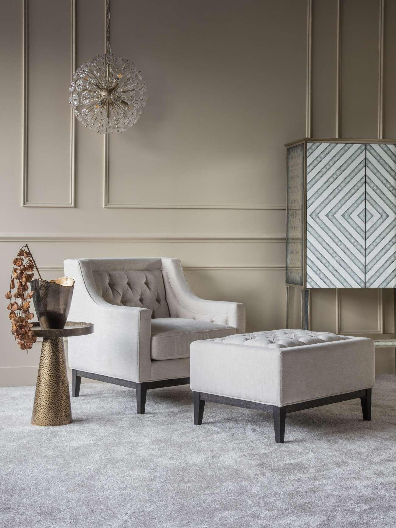Ivory buttoned stool in elegant living room with armchair and modern decor.
