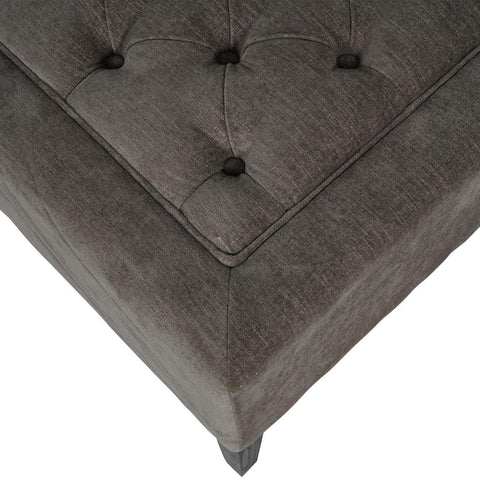 Warm grey fabric stool with button-tufted detail and textured surface.