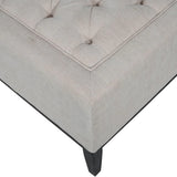 Ivory ottoman corner with button tufting and dark wooden leg.