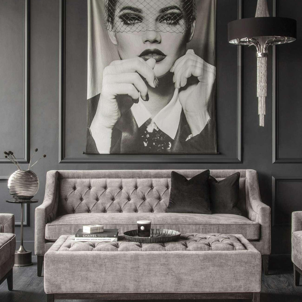 Warm grey ottoman in elegant living room with tufted sofa and modern decor.