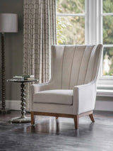 Taupe upholstered chair in elegant living room with side table and patterned curtains.