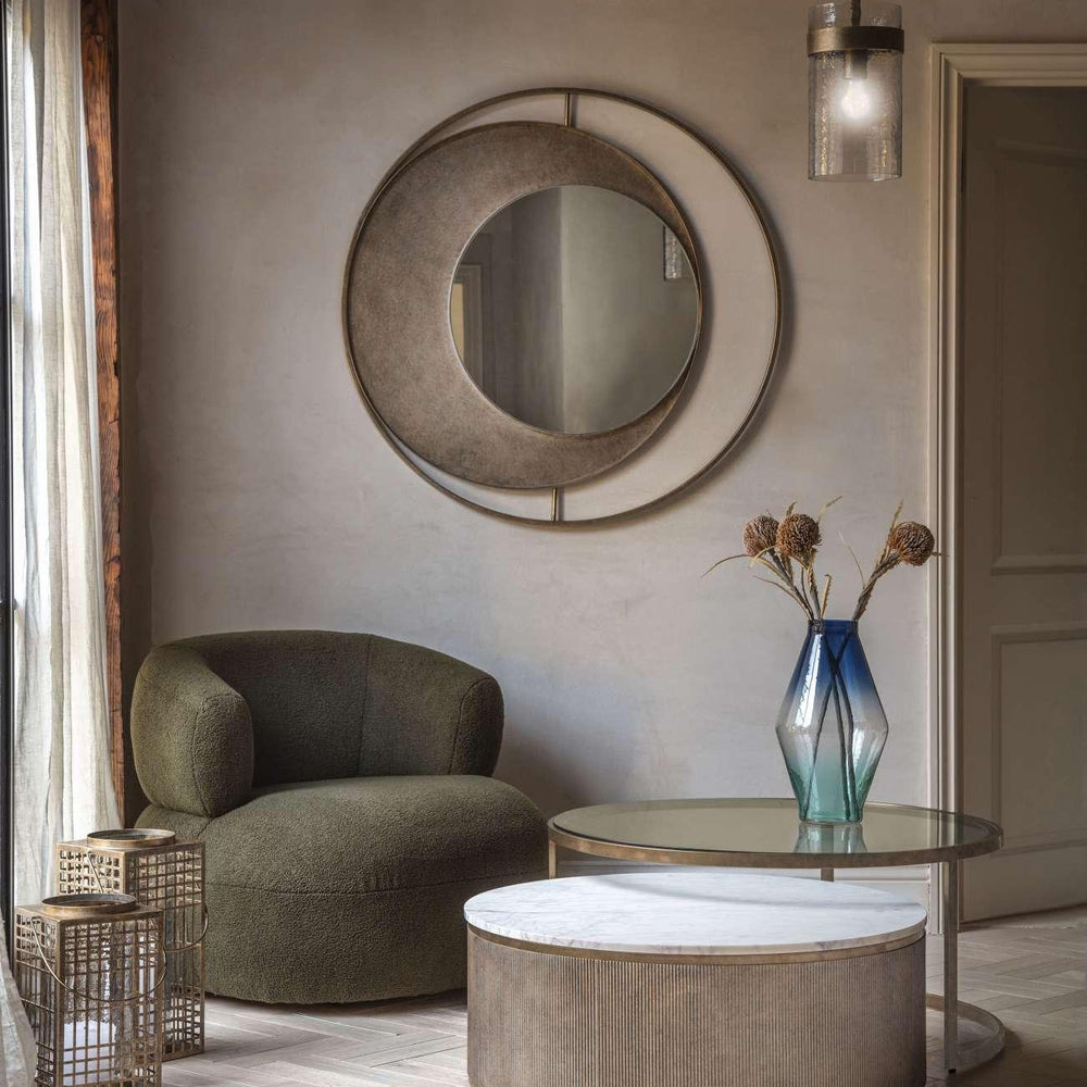 Gold nesting tables in cozy living room with green chair and decorative vase.